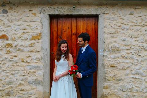 Fotografia de casamento em frente a uma porta de madeira rústica, com noiva em vestido branco e noivo em fato azul. Casal posando para foto,  portfólio de fotógrafo de casamentos, sessão de fotos de casamento. quinta das janelas Casamento civil em Coimbra'
