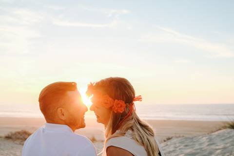 Casal apaixonado ao pôr do sol, trocando olhares cúmplices nas dunas junto ao mar. A luz do sol 
crian um momento único e romântico. pôr do sol, sessão fotográfica de casamento,  praia, natureza.'