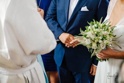 noivos de mãos dadas junto do padre'