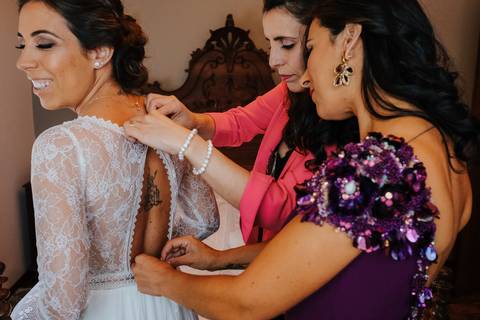 irmão e amiga da noiva ajudam a vestir o vestido de noiva no quarto'