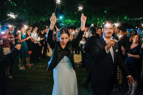 noivos caminham para cortar o bolo com sparkles nas mãos'