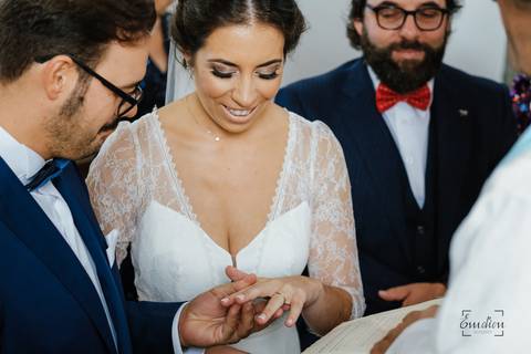 noiva a sorrir quando o noivo lhe coloca a aliança'