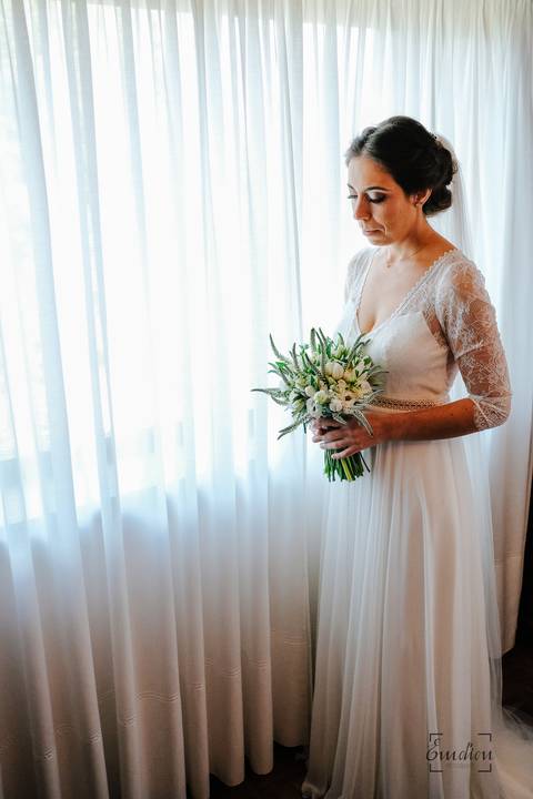 noiva segura no bouquet junto da janela do seu quarto'