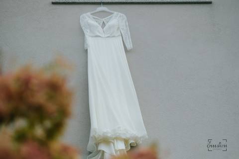 vestido de noiva pendurado na janela do quarto junto a flores do jardim'