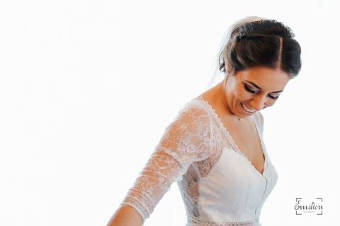 noiva mexe no vestido e sorri junto da janela'