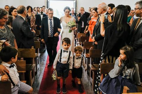 entrada da noiva na igreja acompanhada pelo pai e dois meninos das alianças'