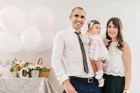 pais seguram a criança no colo no dia do baptizado'