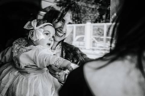 mãe pega ao colo a criança e ficam refletidas no vidro'