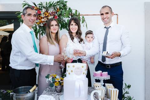 pais e padrinhos brindam com champanhe depois de cortarem o bolo do baptizado'