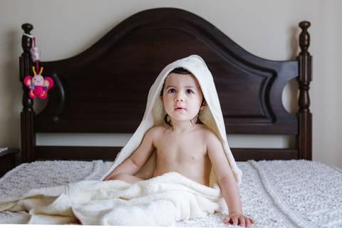 criança sentada na cama depois do banho'
