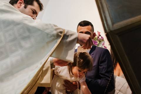 o padre coloca água pela cabeça da criança no momento do baptismo'