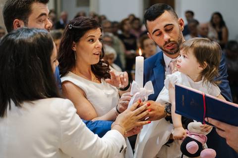 os pais e os padrinhos seguram na vela durante a cerimónia'