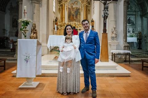 padrinhos tiram foto no altar da igreja com a criança ao colo'