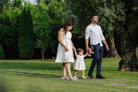 no dia do baptizado os pais passeiam com a filha de mãos dadas'