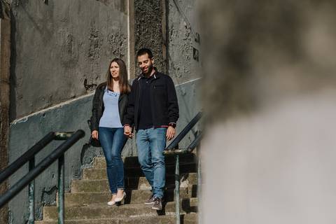 namorados descem escadas no porto de mãos dadas'