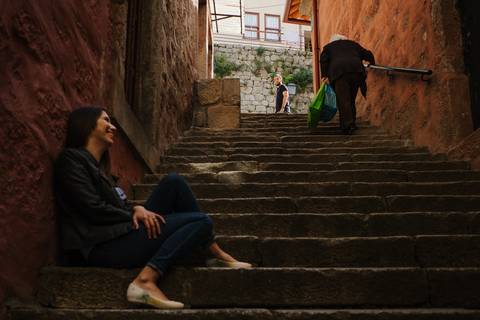 namorada sentada nas escadas à espera do namorado enquanto velhinha sobe as escadas'