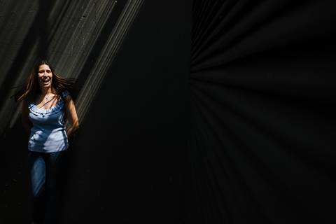 retrato da namorada que sorri encostada à parede a receber raios de sol'