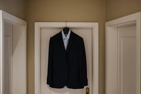 Casaco e camisa do fato do noivo pendurados na porta'