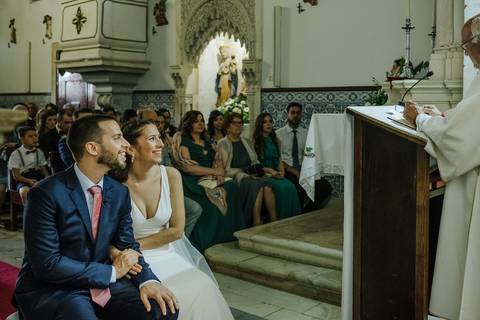 Noivos sorriem para o padre na igreja de Portunhos'