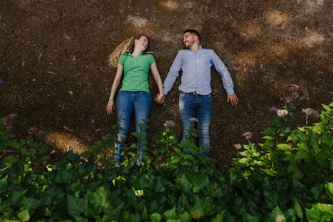 Namorados deitados no chão de mão dada no Jardim Botânico'