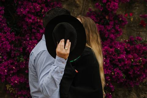 Namorados beijam-se e ocultam beijo com chapéu do rancho, no Jardim Botânico em Coimbra'