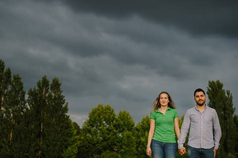 Namorados caminham de mãos dadas no parque verde da cidade de Coimbra'