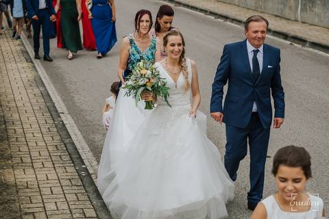 Noiva vai a pé de casa para a igreja com os seus convidados.'