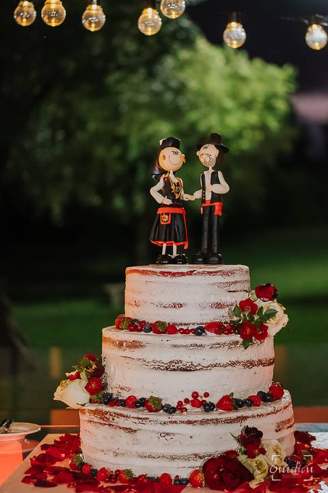 Bolo dos noivos enfeitado com bonecos em miniatura, vestidos com trajes do rancho.'