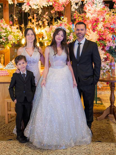 Foto da família em frente à mesa do bolo e doces'