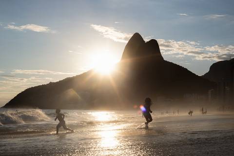 Crianças brincando na praia de Ipanema ao entardecer'