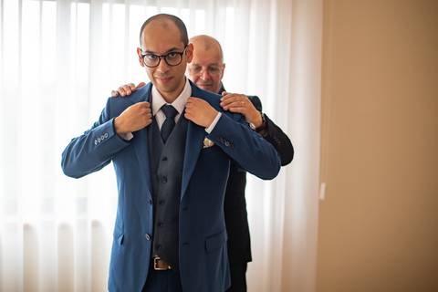 Fotografia de pai do noivo a ajeitar o casaco dele'