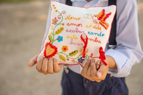 fotografia de menino das alianças a segurar almofada bordada com alianças'