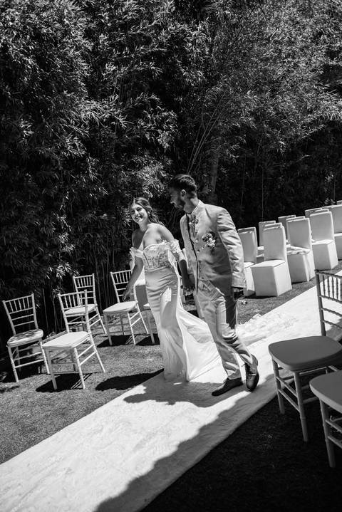 Fotografia a preto e branco de noivos a caminhar de mão dada'