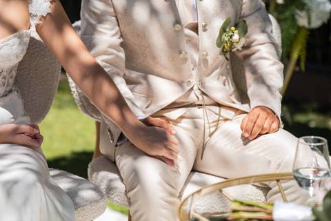 Fotografia de noivos sentados de mãos dadas durante o casamento'