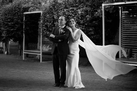 noivos abraçados com véu da noiva a esvoaçar - fotografia de casamento a preto e branco '