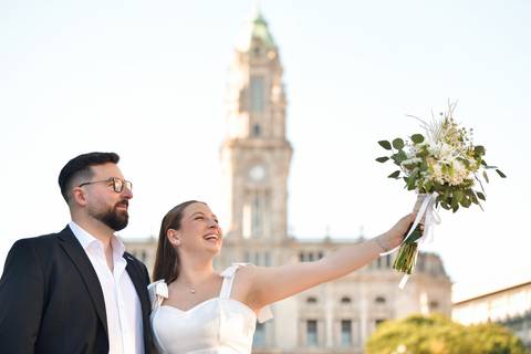 casal a olhar para o ramo da noiva em frente à Câmara do Porto - Sessão fotográfica de pré-wedding'