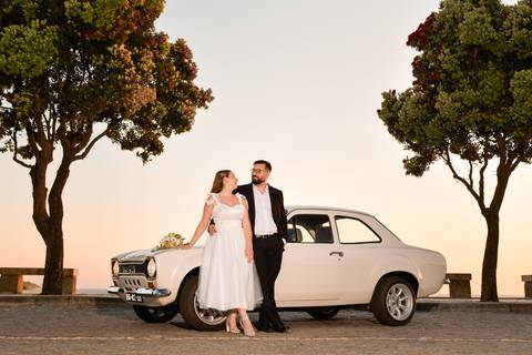 fotografia de casal encostado a um carro a olhar um para o outro'