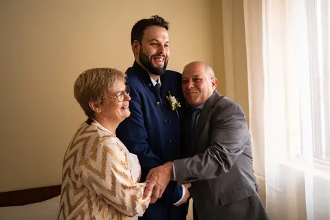 fotografia de casamento do noivo abraçado aos pais'