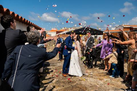 fotografia de casamento de noivos sair da cerimónia enquanto são atiradas pétalas'