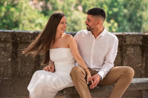 casal sentado num banco a olhar um para o outro - sessão fotográfica na natureza'