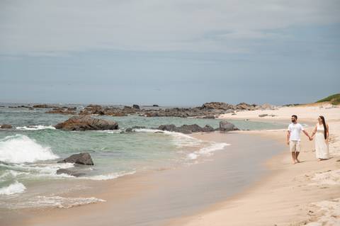  sessão de pré wedding na praia - fotografia de casal de mão dada a caminhar'
