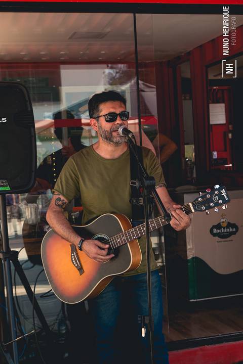 O músico Márcio Fellix Eduardo cantando e tocando violão no Beach Plaay.'