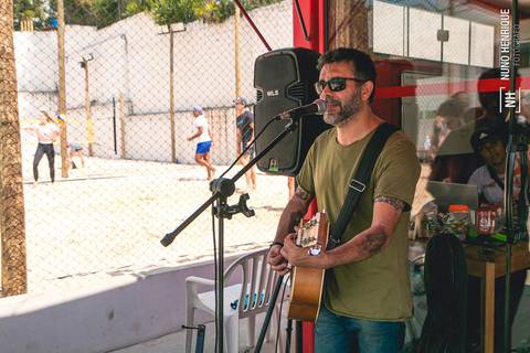 O músico Márcio Fellix Eduardo cantando e tocando violão no Beach Plaay.'