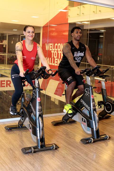 Aula de spinning com alunos pedalando em bicicletas ergométricas na academia'