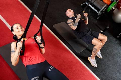 Treino funcional com TRX realizado por alunos durante aula na academia'