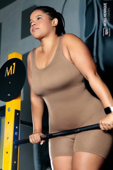 Yara Célia posa apoiada em barra durante ensaio fitness feminino'