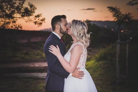Casamento ao ar livre noivos se beijando ao por-do-sol'