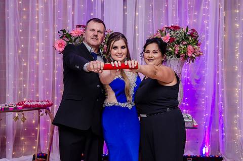Formanda posando com os pais em sua festa de formatura'