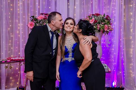 Formanda posando com os pais em sua festa de formatura'