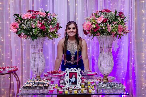 Formanda posando atras da mesa de doces em sua festa de formatura'